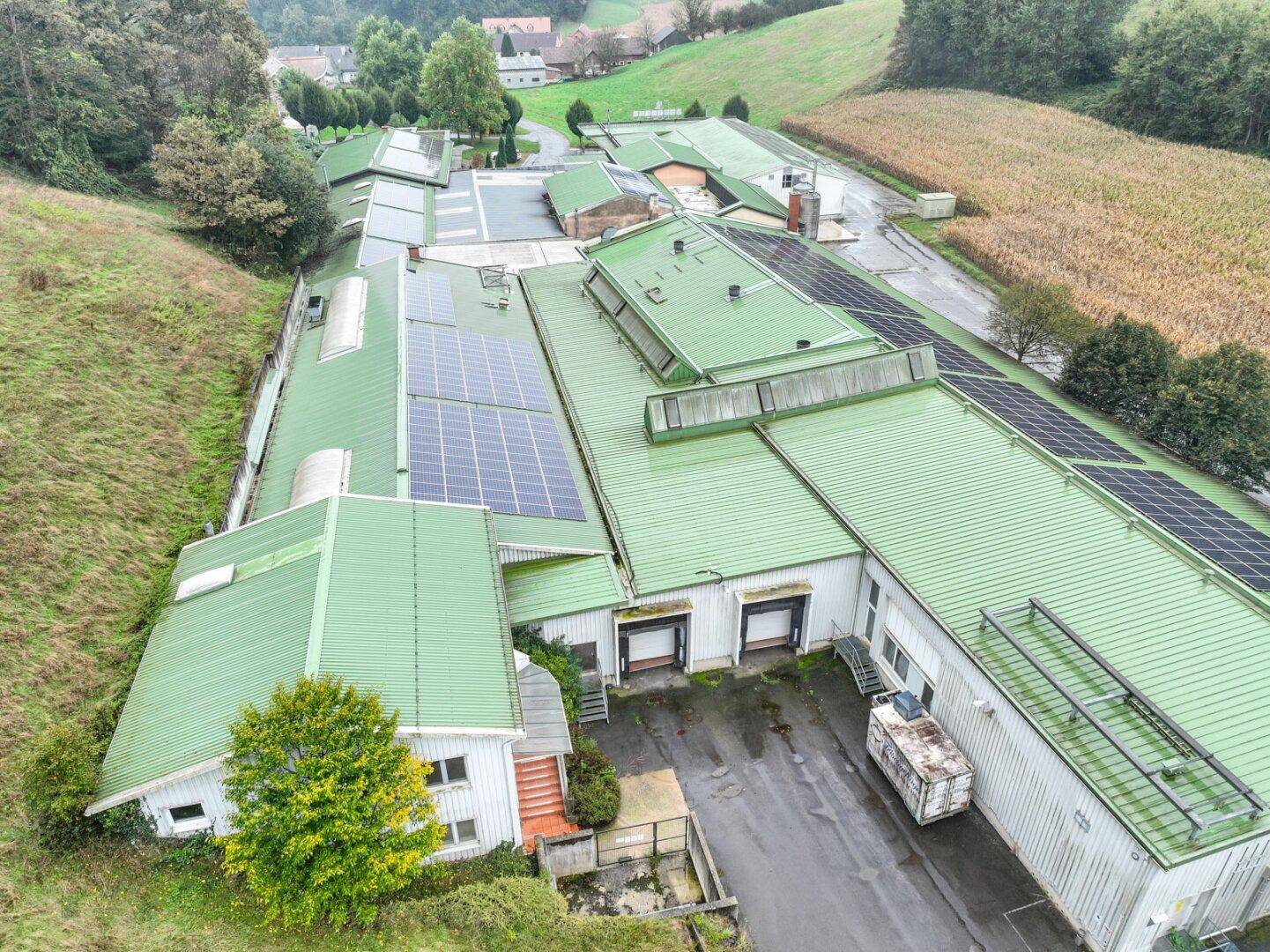 Weitläufige Luftaufnahme des Gewerbegebäudes mit mehreren Laderampen und zahlreichen Solarmodulen auf den Dächern.
