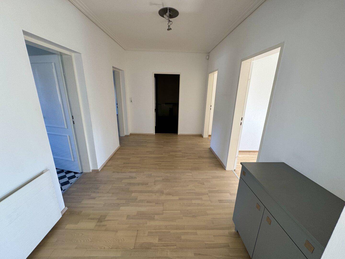 Flur mit hellem Parkettboden und einem Schrank, der Stauraum bietet.