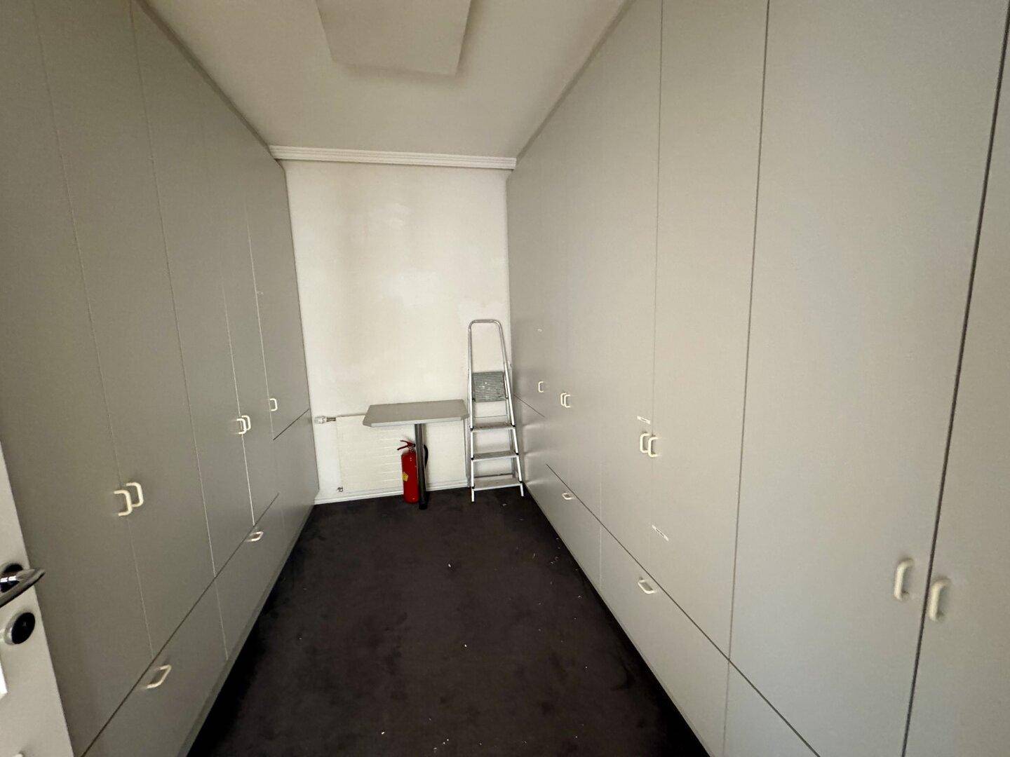 Praktischer Abstellraum mit vielen Einbauschränken und Teppichboden für zusätzlichen Stauraum.