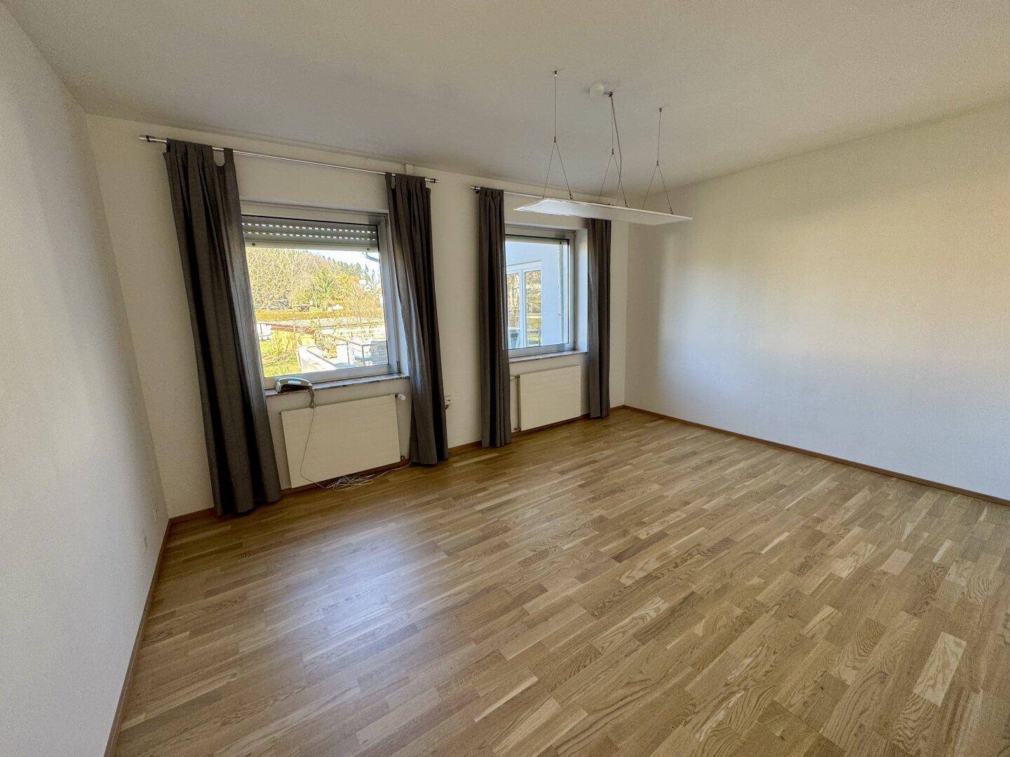 Geräumiges Zimmer mit Parkettboden und zwei Fenstern, die für gute Belichtung sorgen.