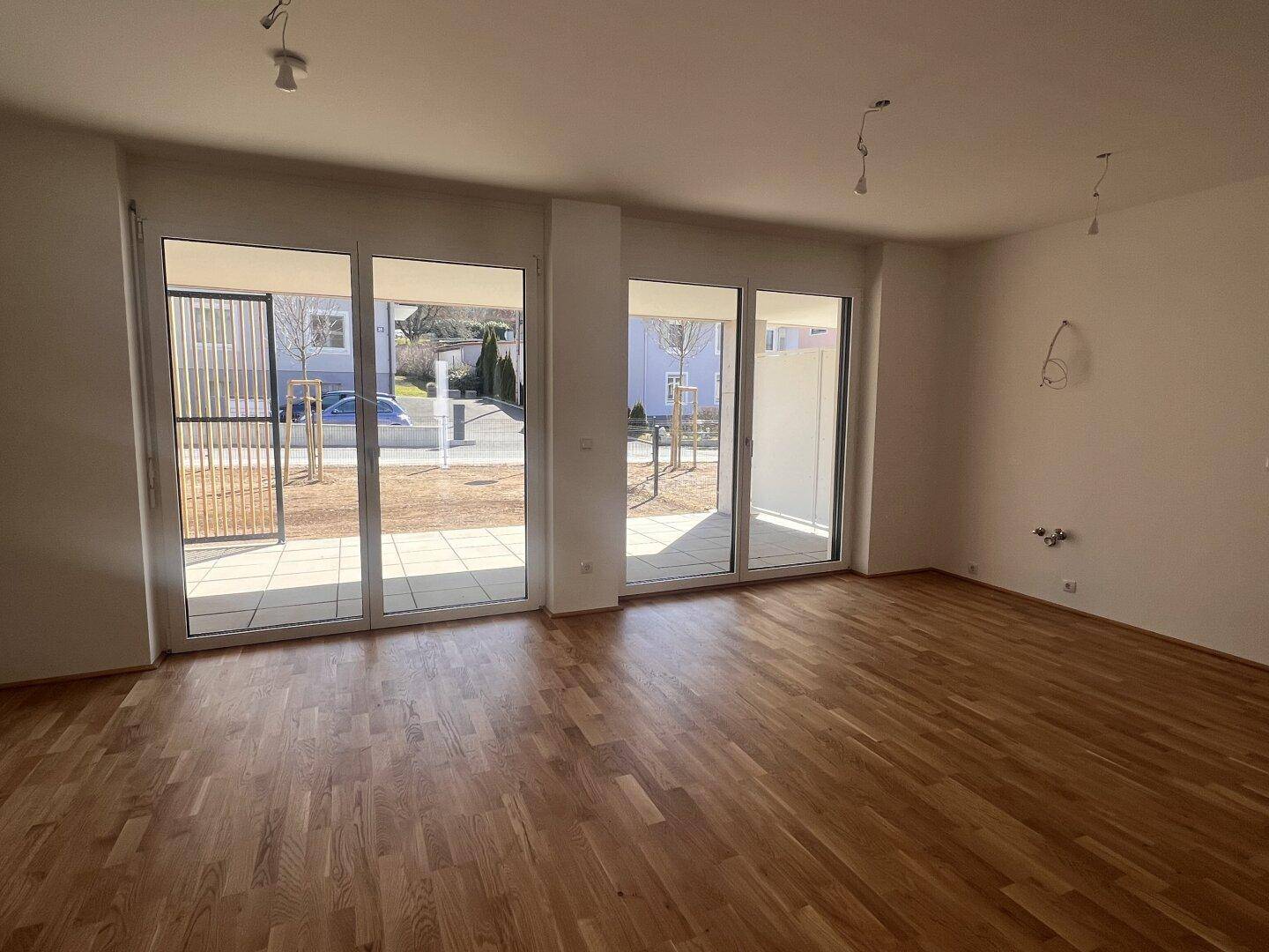 Helles Wohnzimmer mit Eichenparkettboden und großen Schiebetüren zur Terrasse.