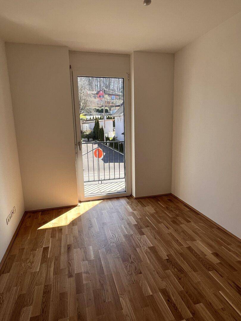 Helles Zimmer mit Holzboden und französischem Balkon, ideal als Kinder- oder Gästezimmer.