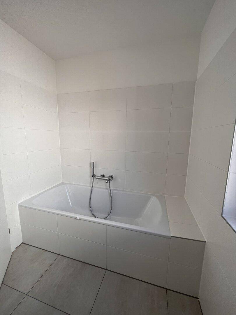 Modernes Badezimmer mit eingebauter Badewanne und weißen Fliesen, bietet Komfort und Funktionalität.