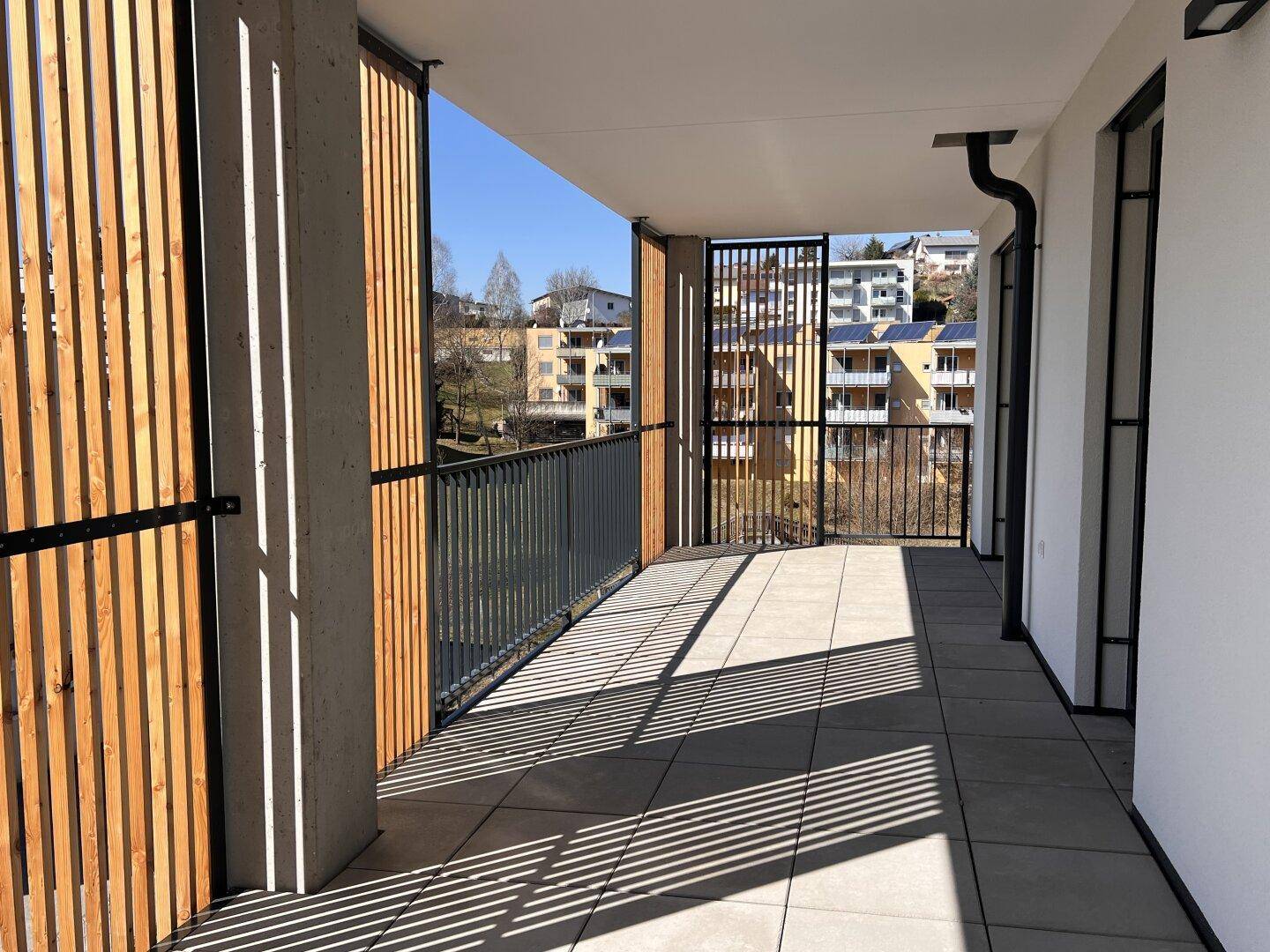 Geräumiger Balkon mit Fliesenboden und Holzlamellen als Sichtschutz, bietet Weitblick.