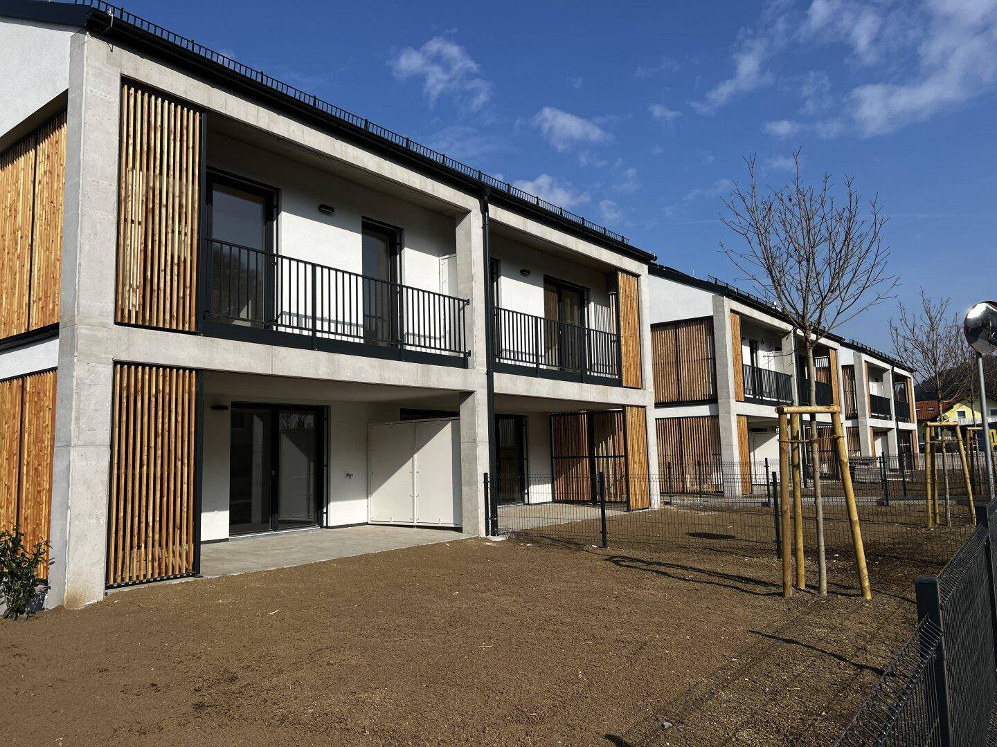 Reihenhäuser mit modernen Holzlamellen und Balkonen in einer neuen Wohnsiedlung.