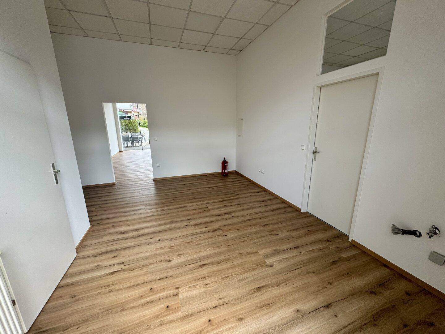 Geräumiger Gewerberaum mit Laminatboden und weißen Wänden, bietet flexible Gestaltungsmöglichkeiten.