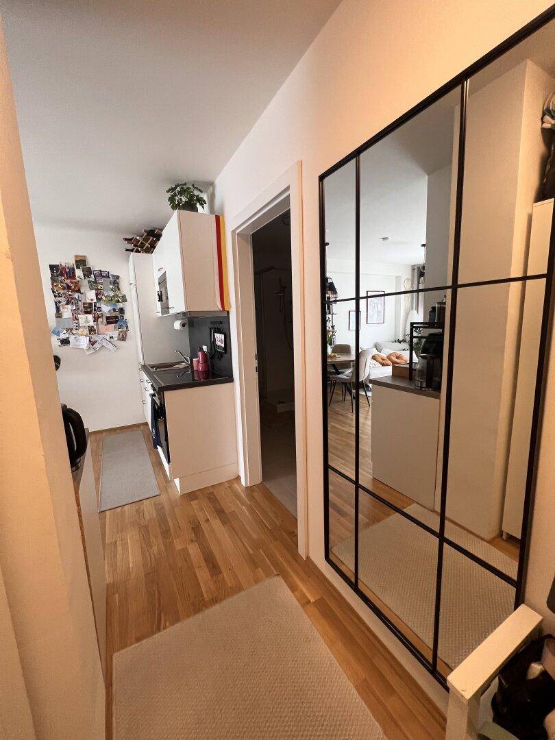 Flur mit Holzparkett und einem großen Spiegel, der den Blick in den Wohnbereich reflektiert.