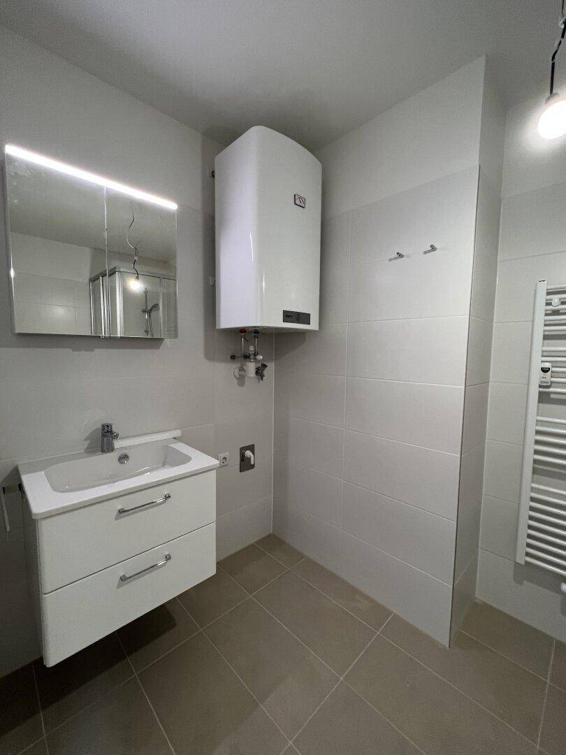 Badezimmer mit Waschbecken, Spiegelschrank und Warmwasserboiler an der Wand.