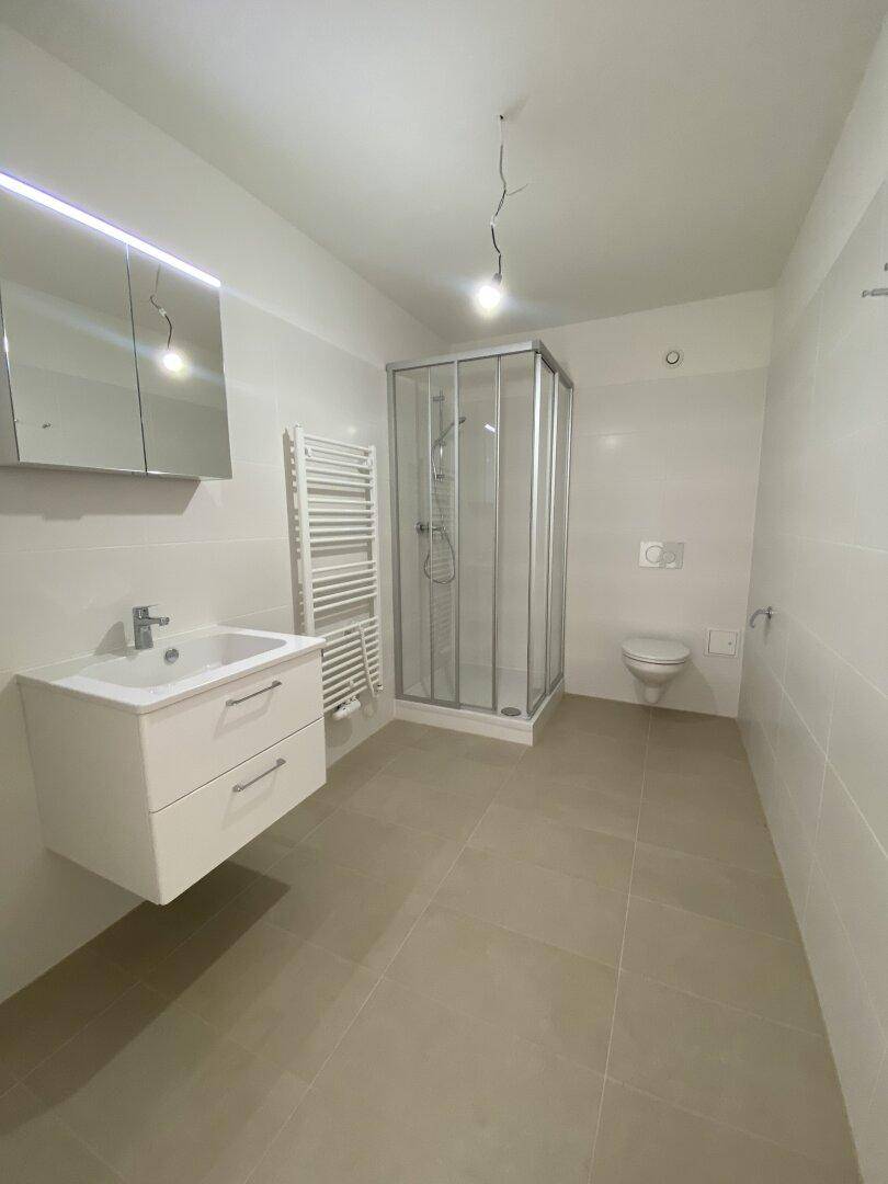 Helles Badezimmer mit Duschkabine, Waschtisch, WC und beheiztem Handtuchhalter.