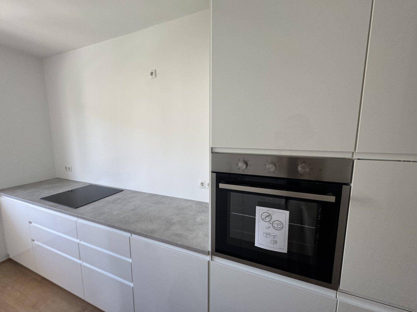 Detailansicht der modernen Küche mit integriertem Backofen und Induktionskochfeld.
