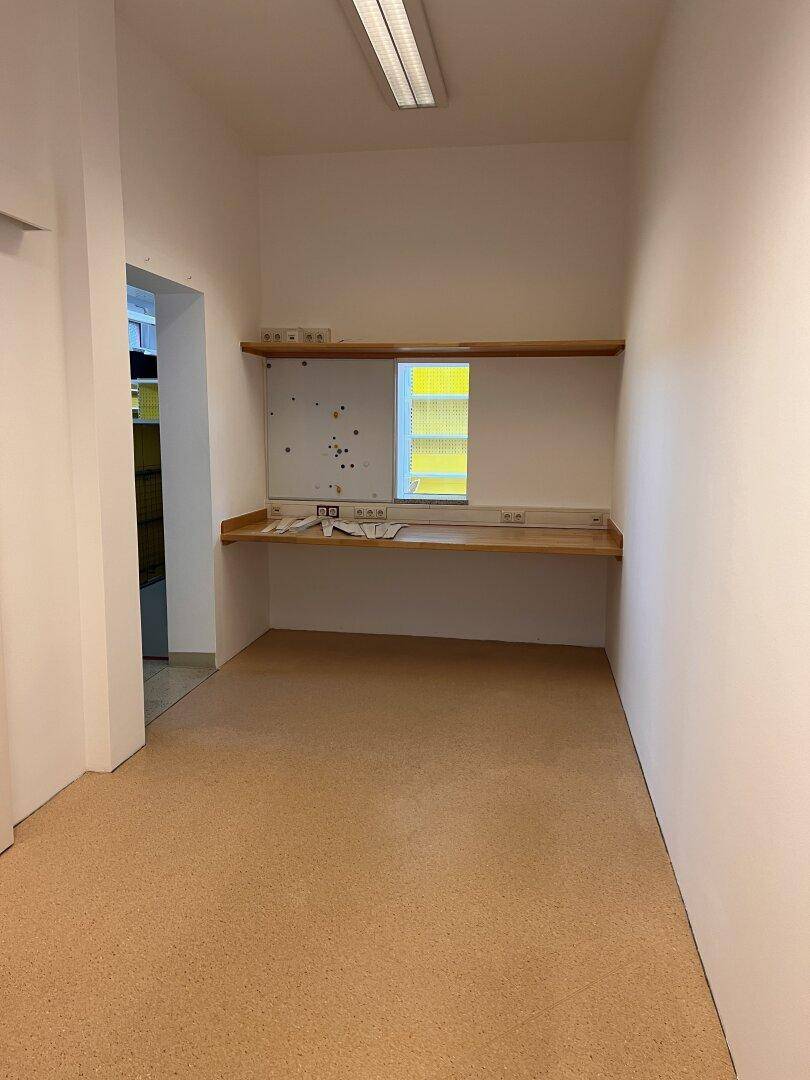Kleiner Büroraum mit Holztheke und Steckdosen, ideal als Arbeitsbereich oder Lager.