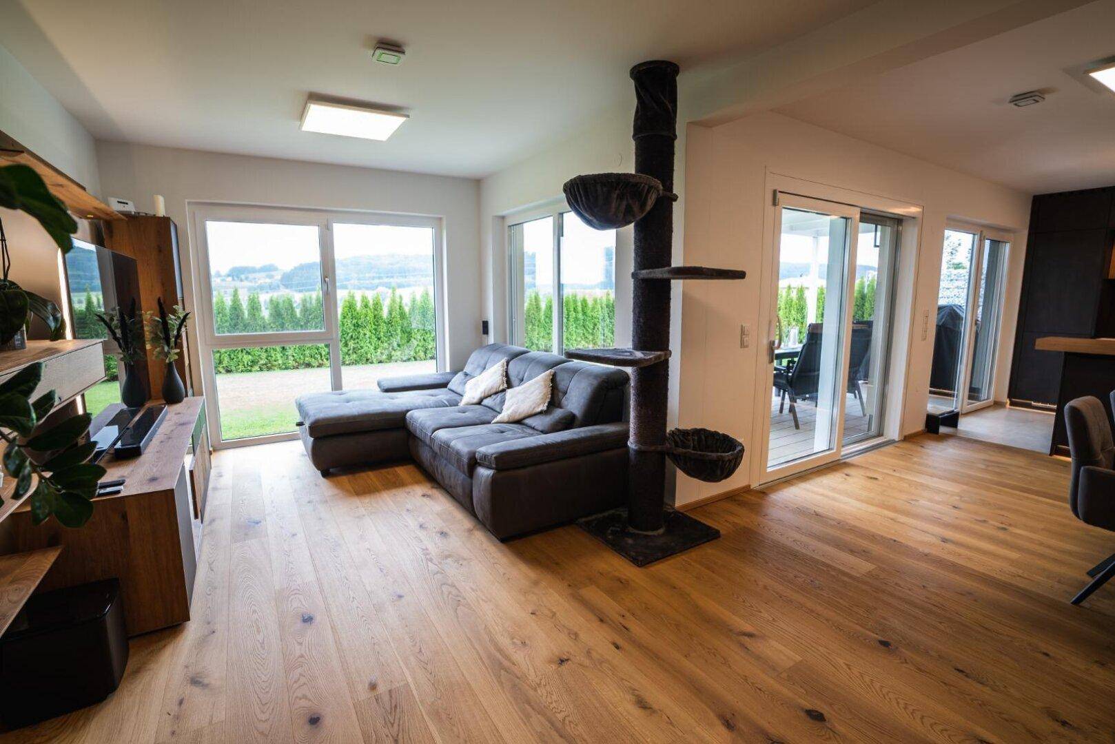 Helles Wohnzimmer mit großzügigen Fensterfronten und Zugang zur Terrasse.