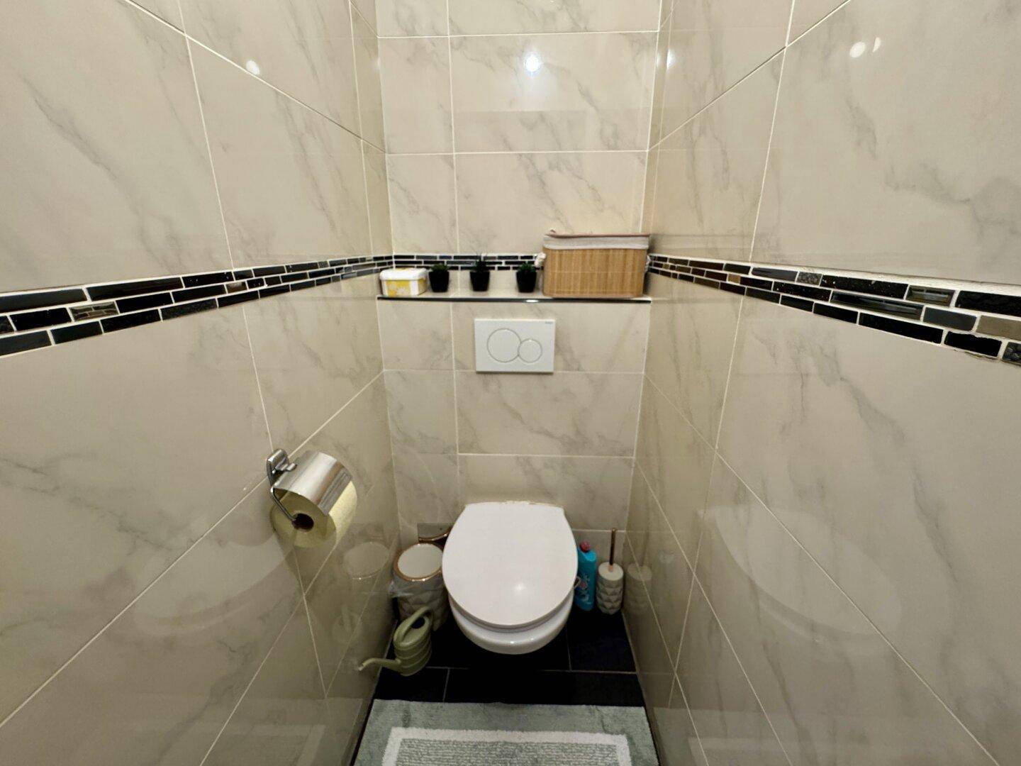Kleines, modern gefliestes Gäste-WC mit Wand-WC und minimalistischem Design.
