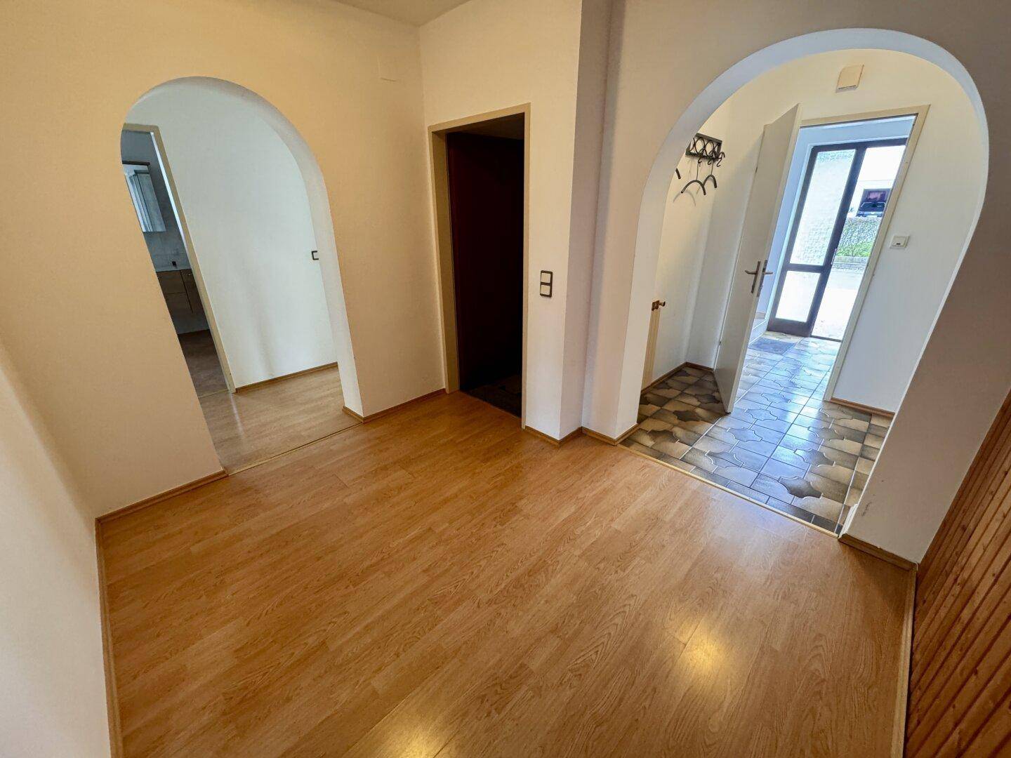 Flur mit Laminatboden und Rundbögen, der zu verschiedenen Räumen führt.