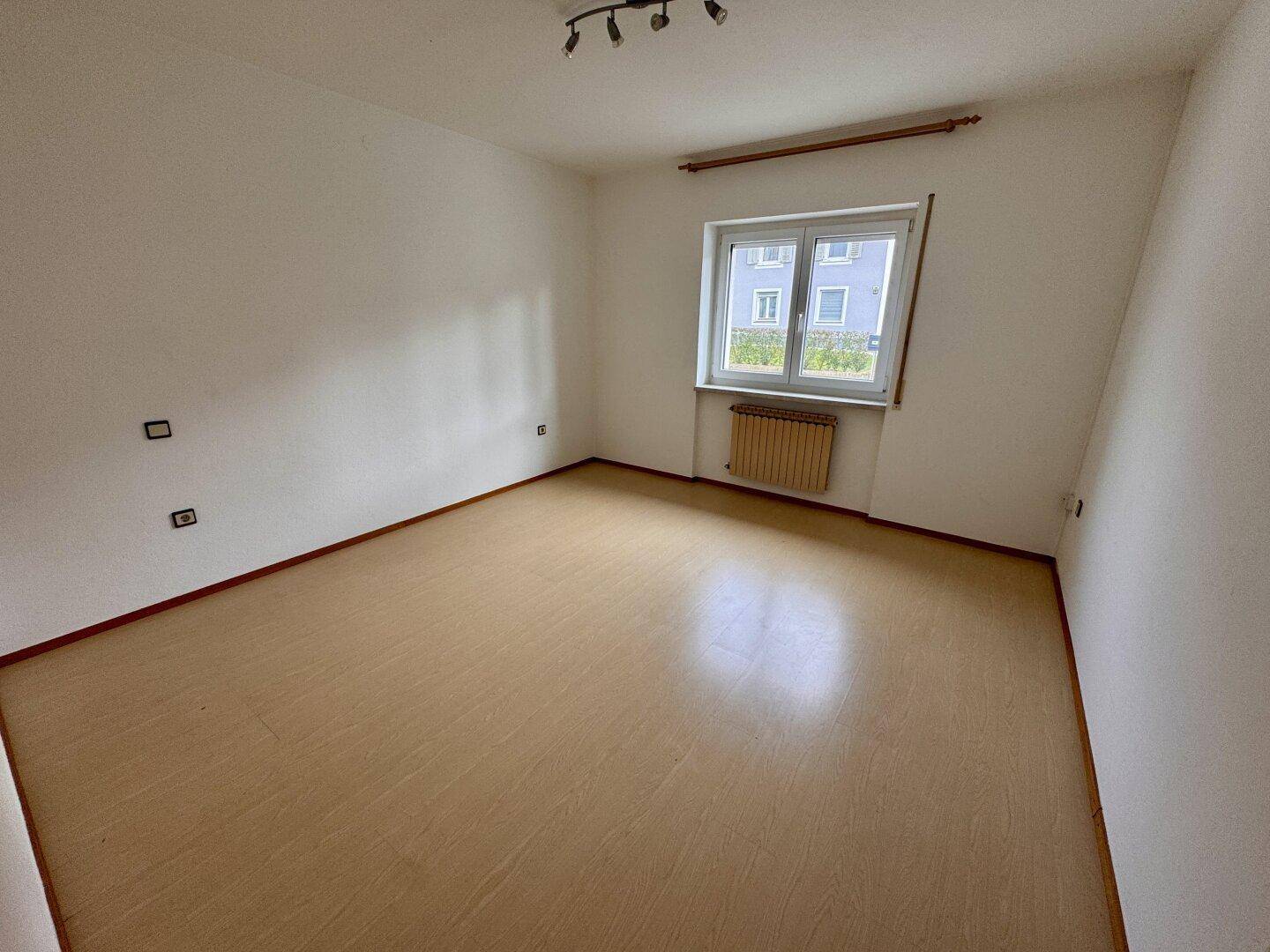 Geräumiges Schlafzimmer mit Laminatboden und Fenster, bietet viel Platz.