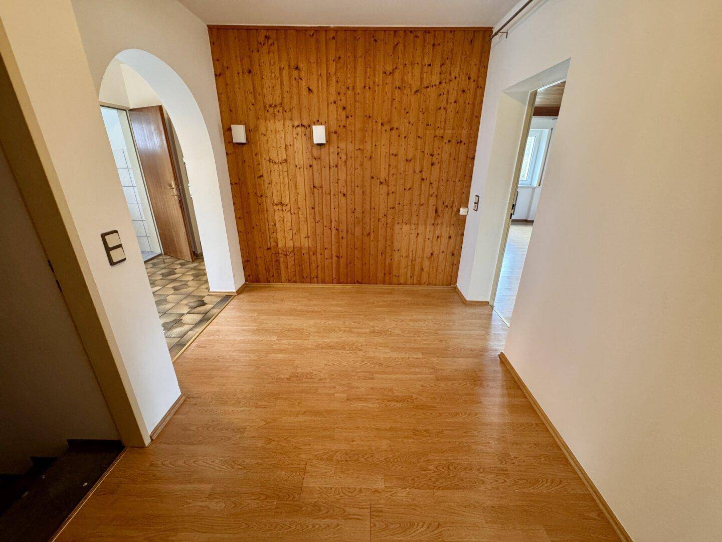 Flur mit Laminatboden und einer Holzwandverkleidung, die einen rustikalen Akzent setzt.