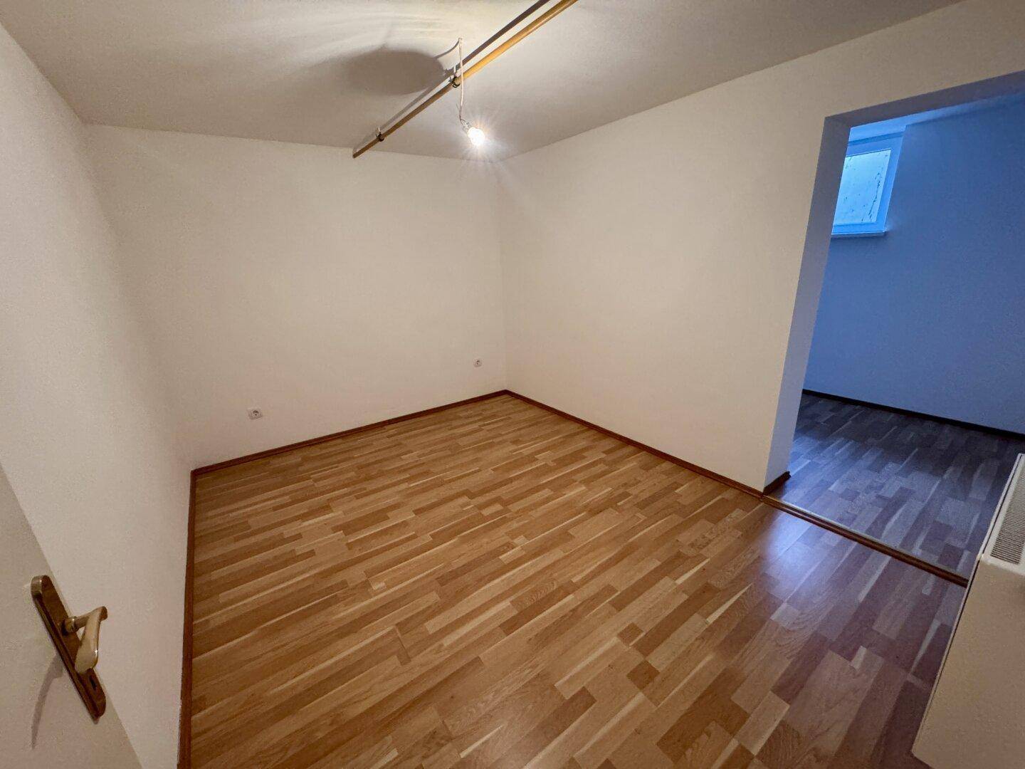 Schlafzimmer mit Laminatboden und schlichten Wänden, bereit zur Einrichtung.