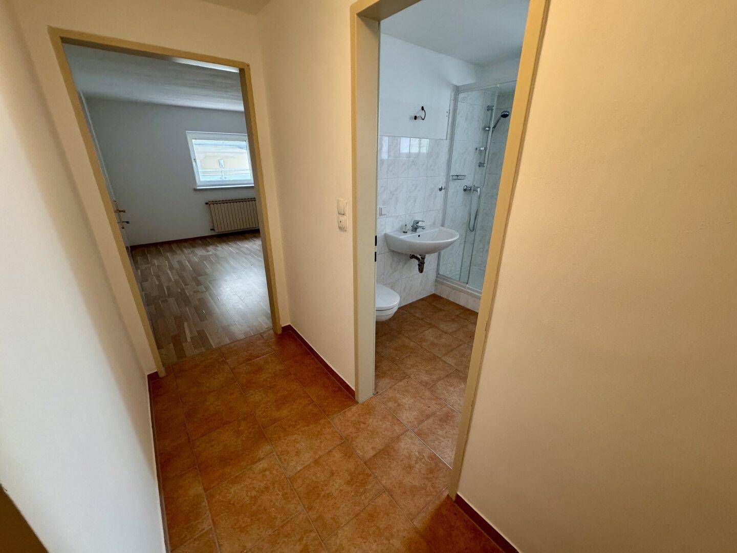 Flur mit Fliesenboden, der zu einem Badezimmer und einem weiteren Zimmer führt.