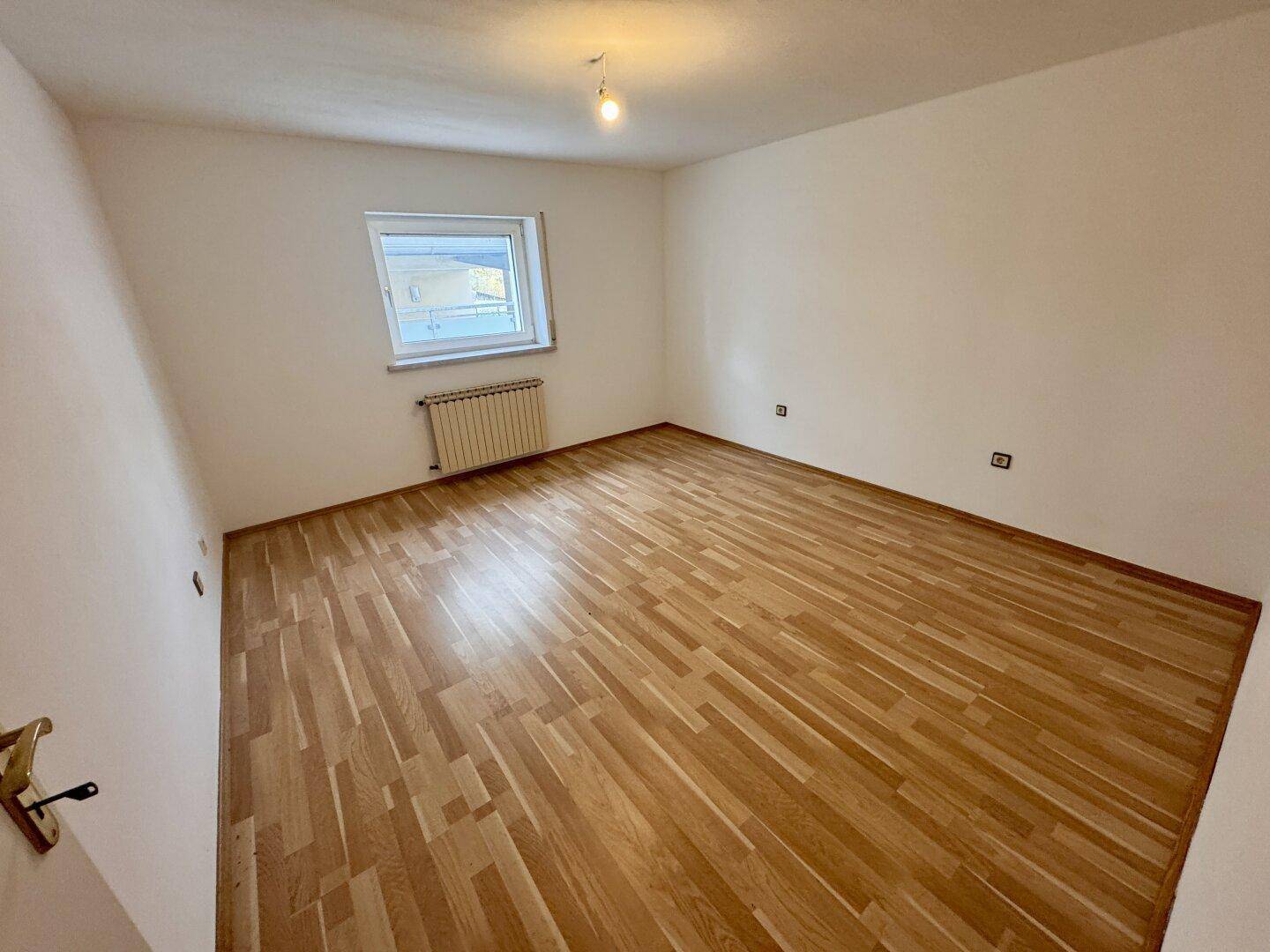 Helles Schlafzimmer mit Laminatboden und Fenster, bietet eine neutrale Basis für die Gestaltung.