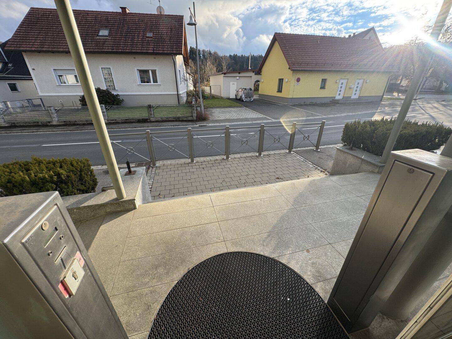 Eine Außenansicht mit einer Straße, Häusern und einem Parkplatz unter einem bewölkten Himmel.
