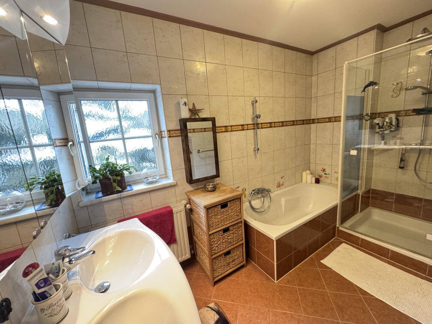 Geräumiges Badezimmer mit Badewanne, Dusche, Doppelwaschbecken und Fenster.