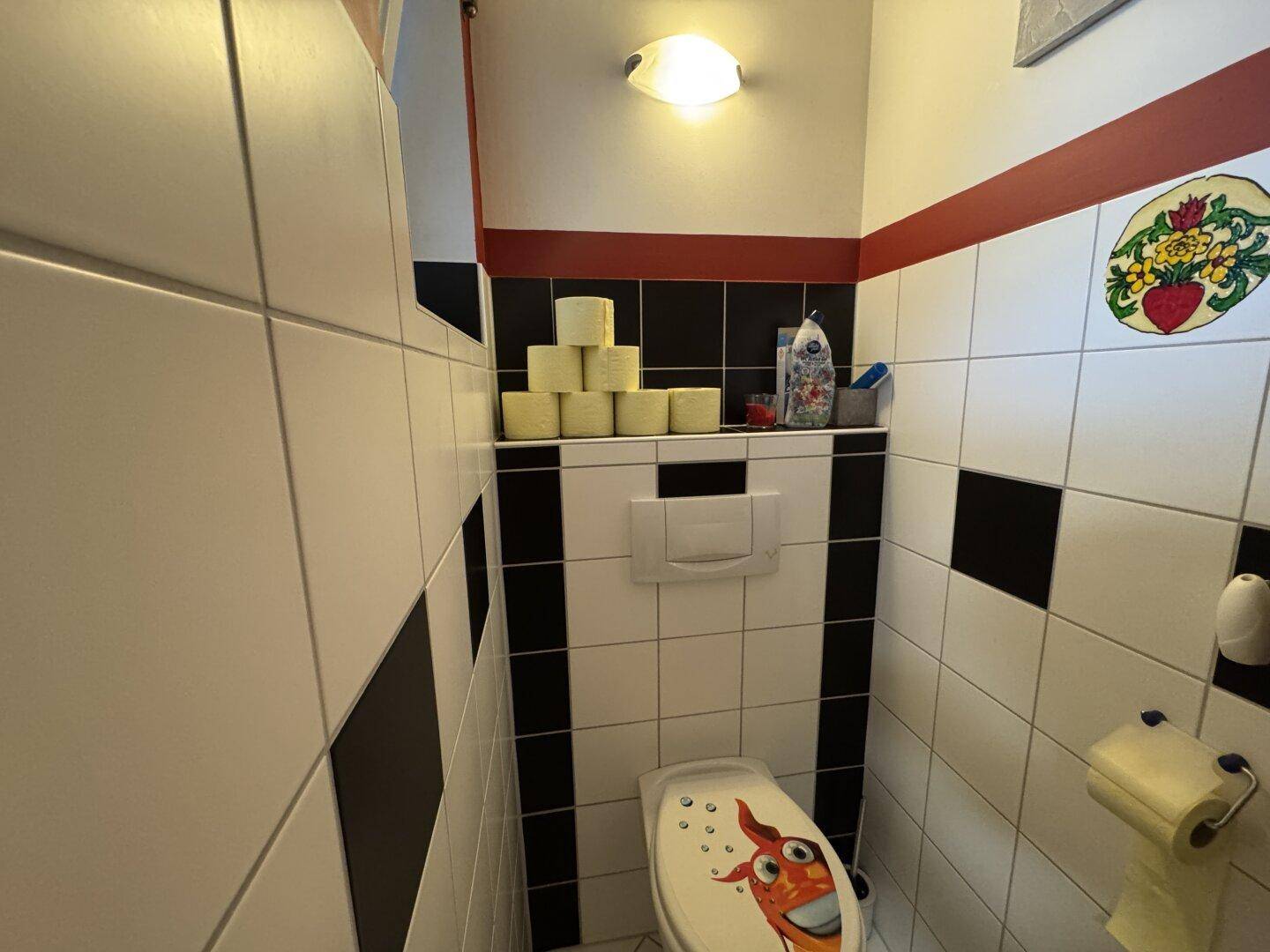 Kleines Gäste-WC mit Toilette, Waschbecken und schwarz-weiß gefliesten Wänden.