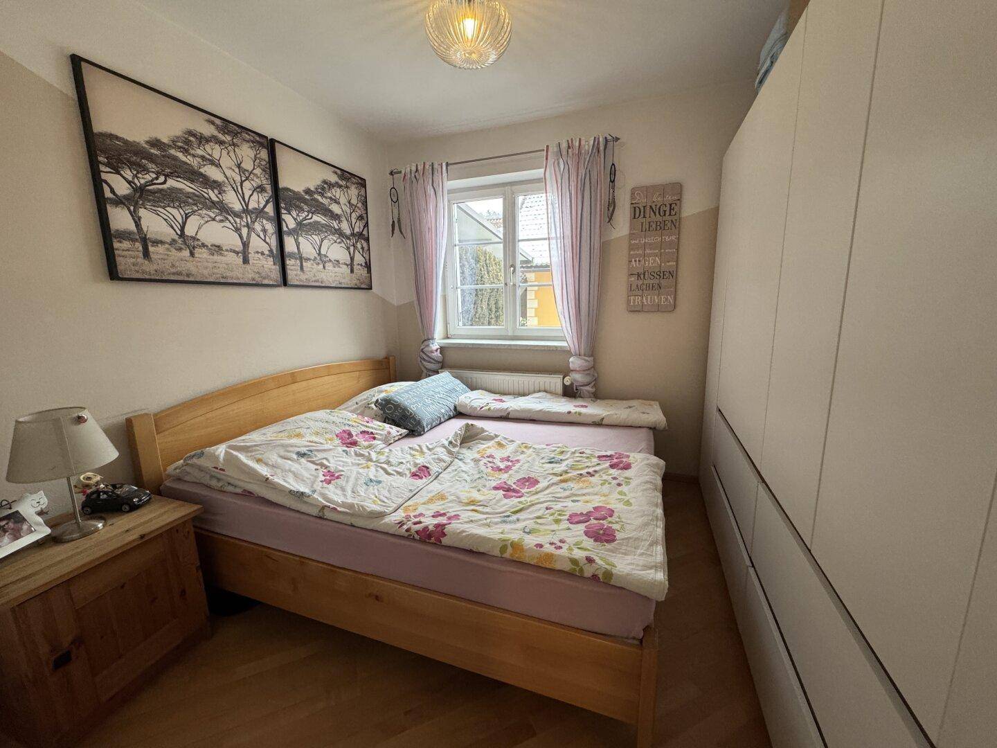 Gemütliches Schlafzimmer mit Holzbett, großem Kleiderschrank und Fenster.