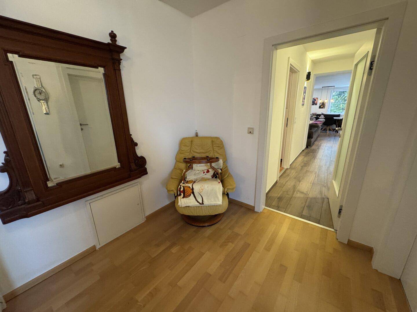 Heller Flur mit Spiegel, Sessel und Blick in den angrenzenden Wohnbereich.