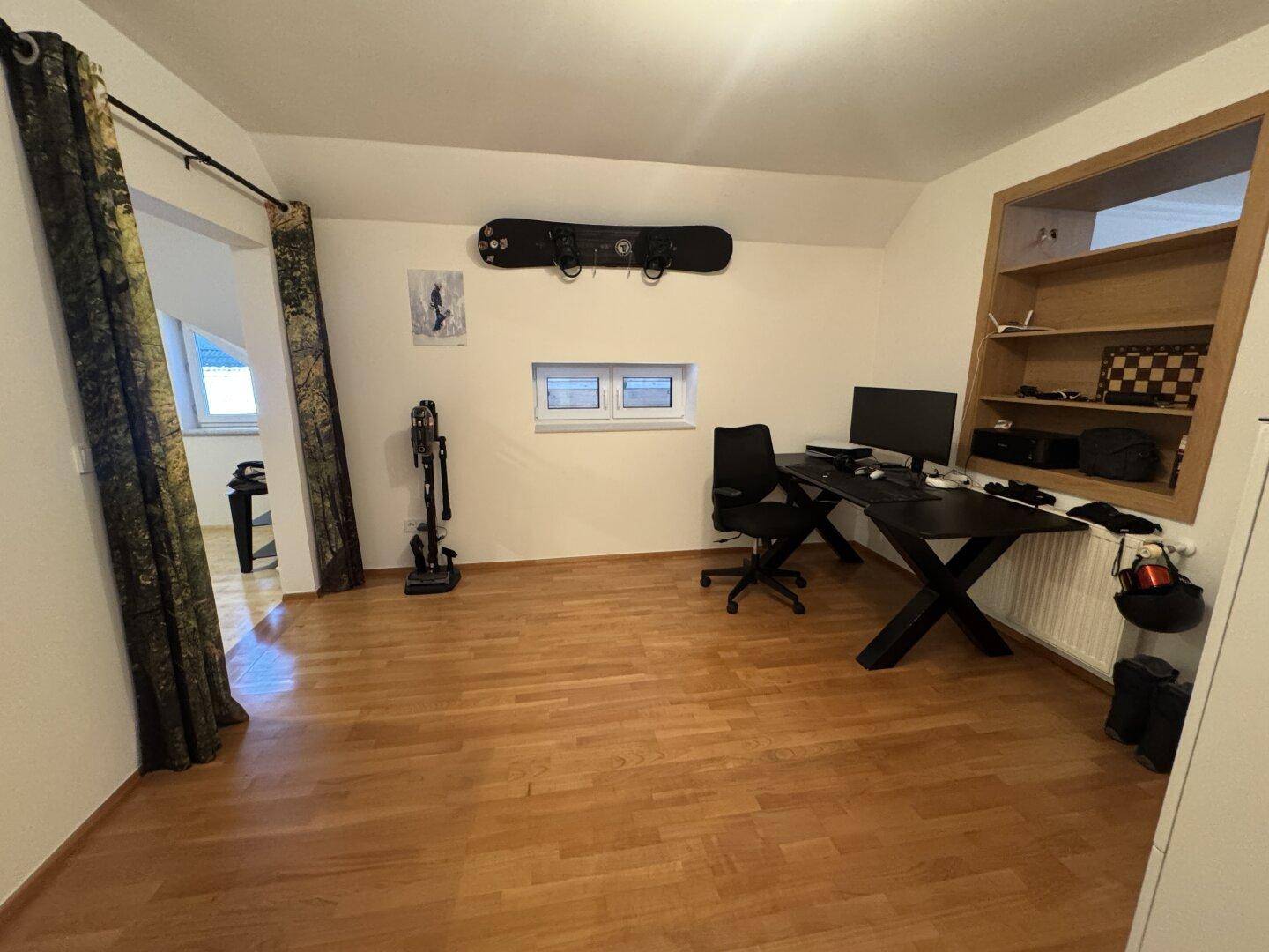 Helles Arbeitszimmer mit Holzboden, Schreibtisch und Dachschräge.