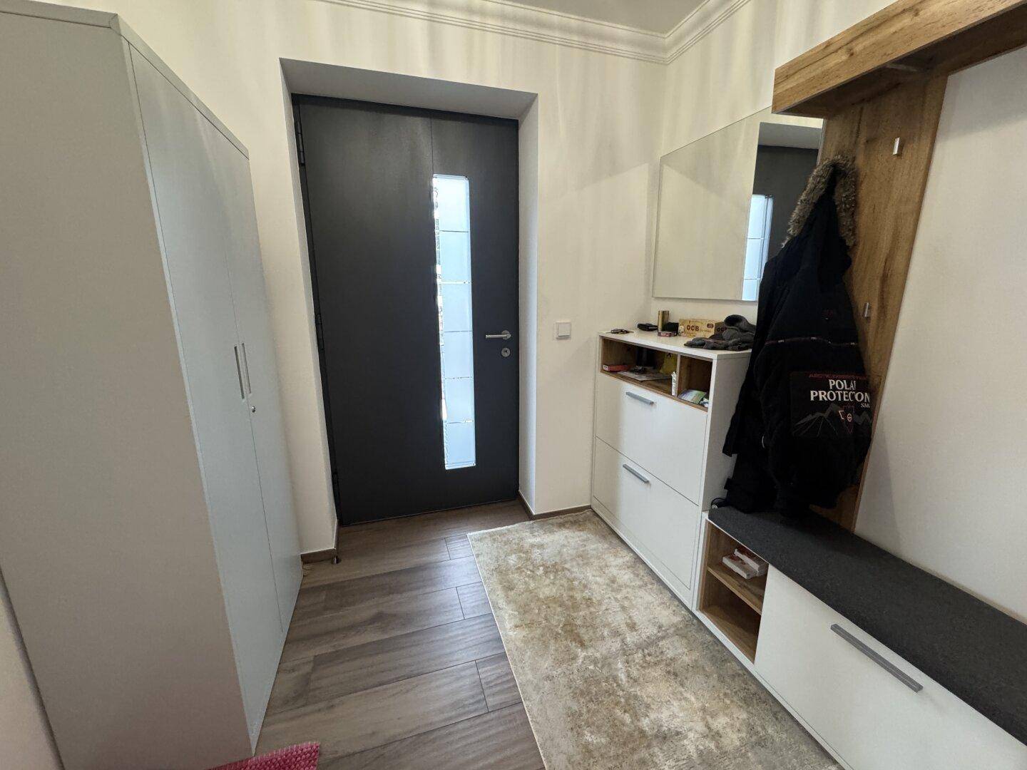 Heller Eingangsbereich mit Garderobe, Schuhschrank und Holzboden.