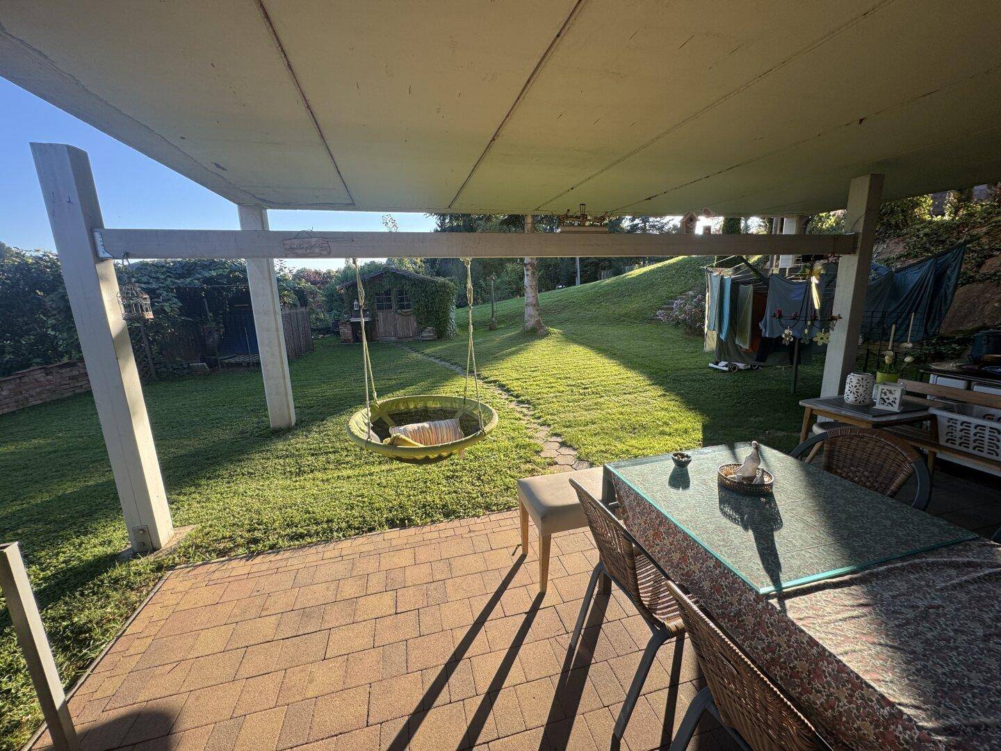 Überdachte Terrasse mit Sitzgelegenheiten und Blick in den grünen Garten.