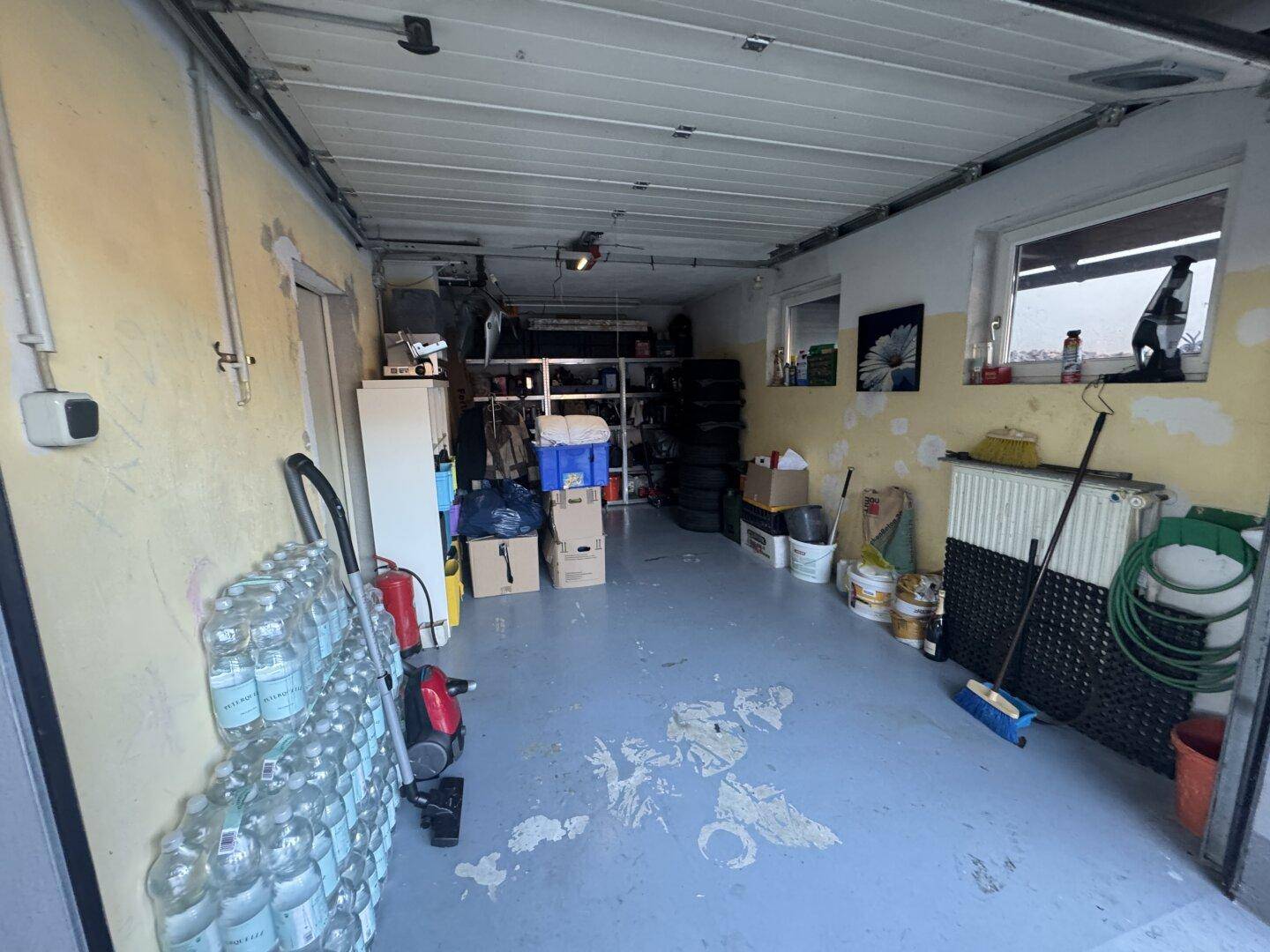 Geräumige Garage mit Lagerregalen, Reifen und verschiedenen Gegenständen.