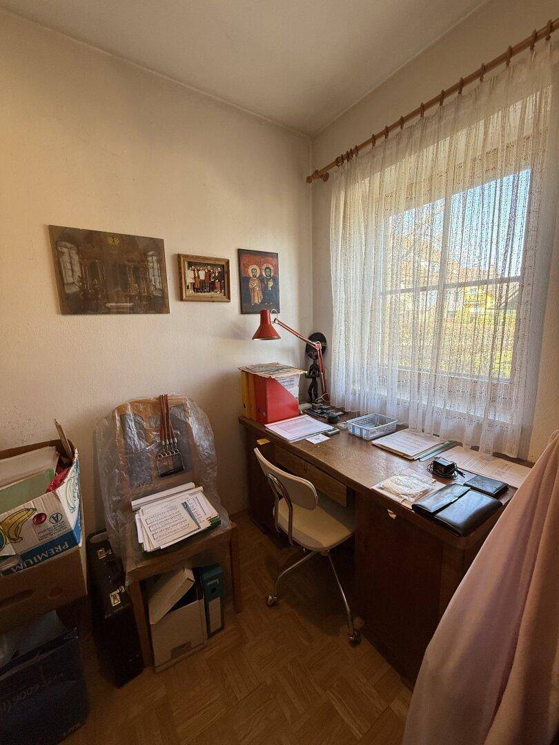 Helles Arbeitszimmer mit Holzboden, Schreibtisch und großem Fenster, ideal für konzentriertes Arbeiten.
