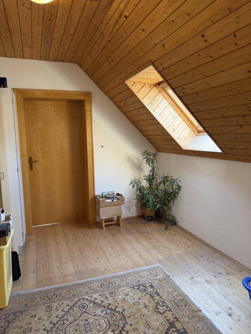 Ausgebauter Dachboden mit Holzdecke, Holzboden und Dachfenster, das viel Licht hereinlässt.