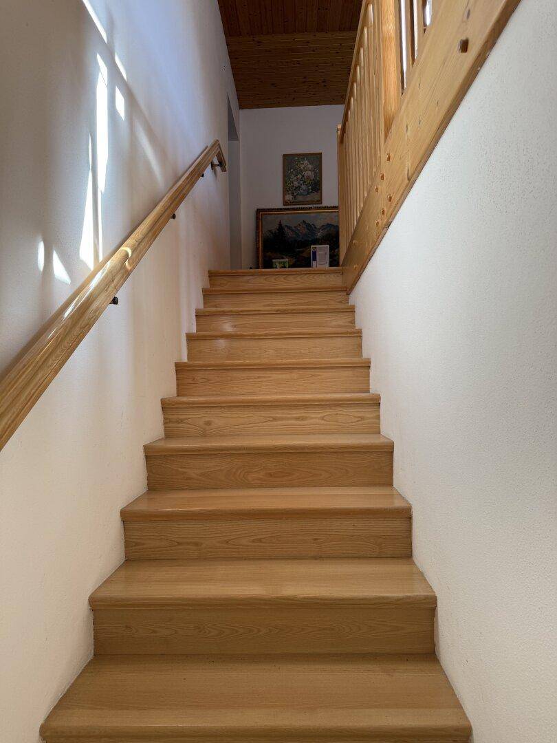 Holztreppe mit Handlauf, die die verschiedenen Etagen des Hauses auf natürliche Weise verbindet.