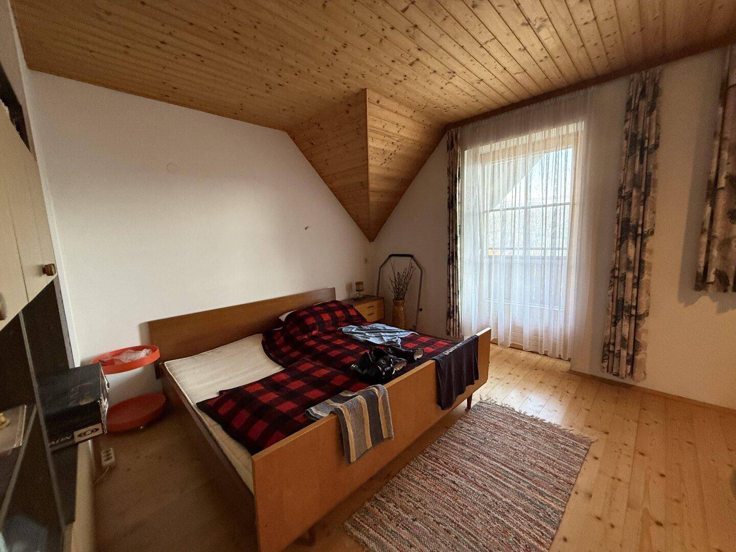 Schlafzimmer im Dachgeschoss mit Holzboden, Holzdecke und schrägen Wänden, schafft eine gemütliche Atmosphäre.