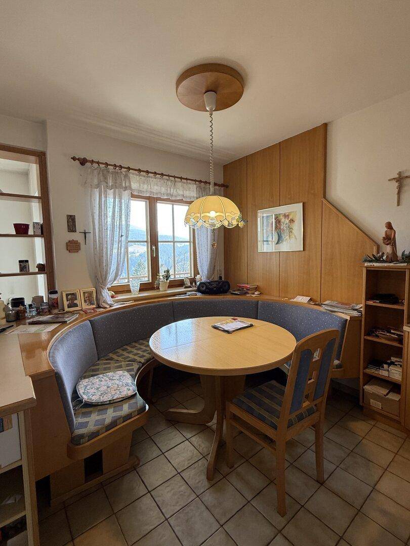 Gemütlicher Essbereich in der Küche mit Eckbank, Holztisch und Fenster mit Blick ins Grüne.