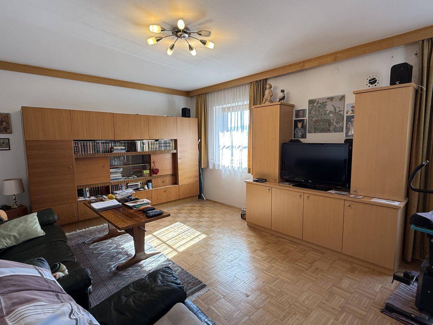 Geräumiges Wohnzimmer mit Parkettboden, Holzmöbeln und großem Unterhaltungssystem für entspannte Abende.