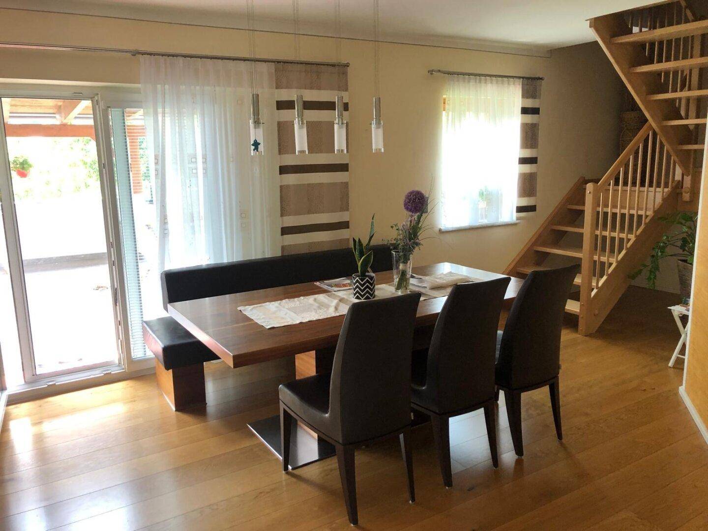 Heller Wohn- und Essbereich mit Holzboden, großem Esstisch und Zugang zur Terrasse.