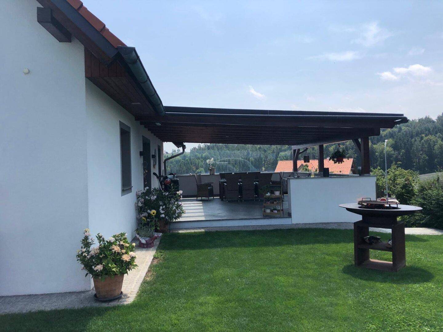 Großer Garten mit Rasenfläche, überdachter Terrasse und Grillbereich im Freien.