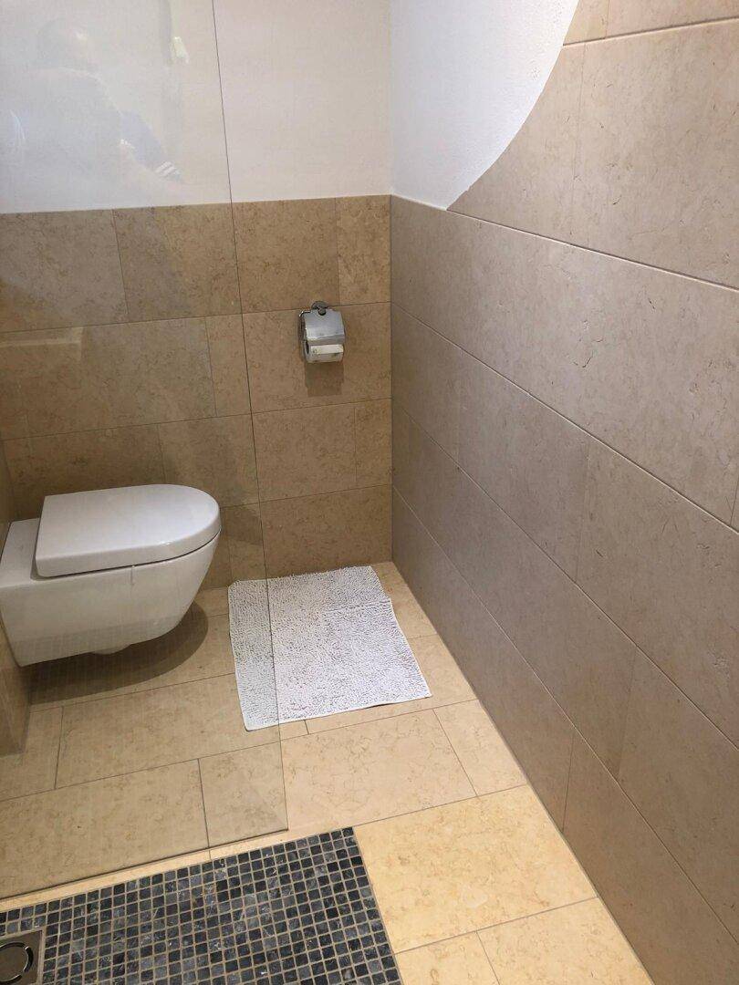 Wandhängendes WC in einem hell gefliesten Badezimmer mit moderner Ausstattung.