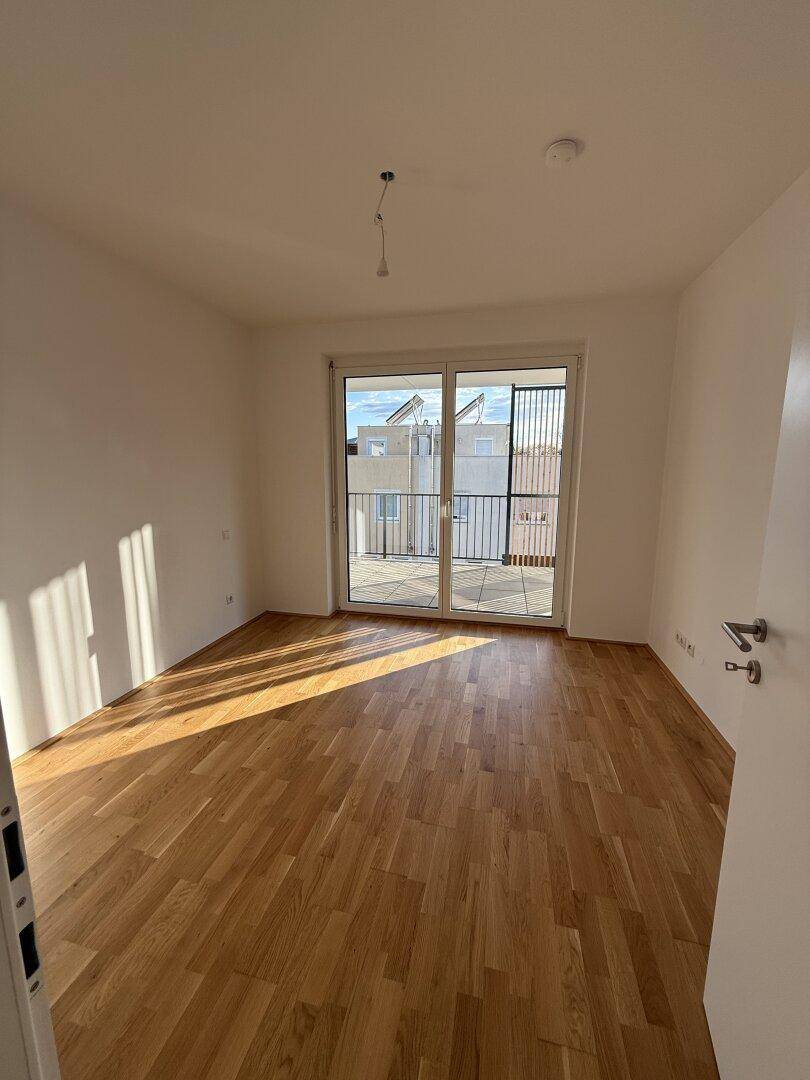 Helles Schlafzimmer mit Parkettboden und direktem Zugang zur Terrasse oder Balkon.