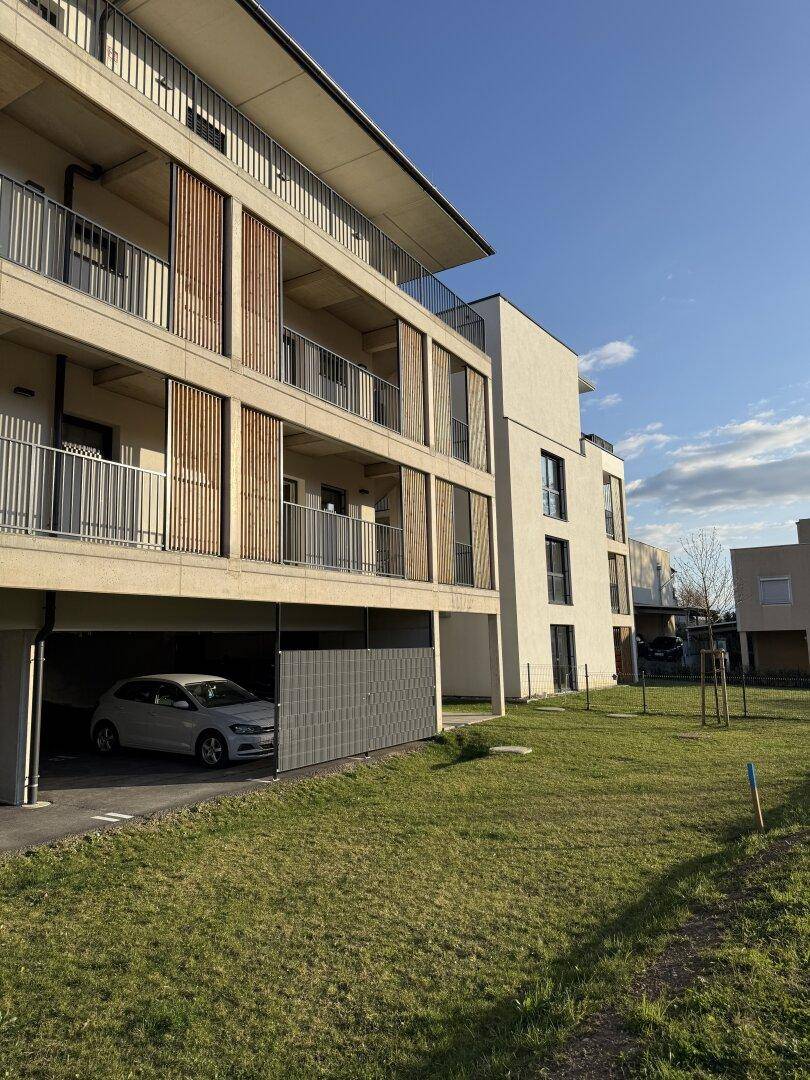 Moderne Wohnanlage mit begrüntem Außenbereich und Tiefgaragenzufahrt.