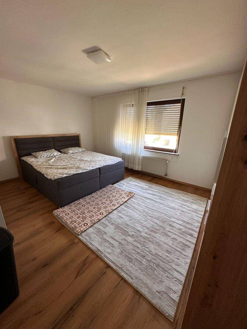 Schlafzimmer mit Doppelbett, Holzboden und Fenster mit Rollladen für Privatsphäre.
