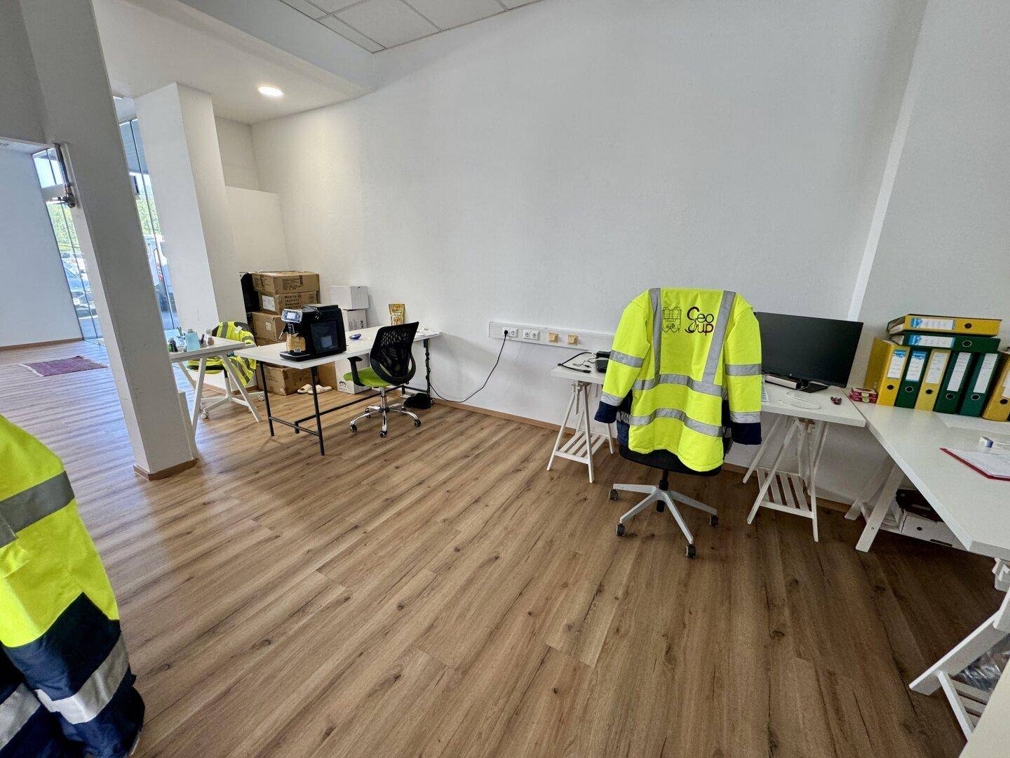 Moderner Bürobereich mit hellen Wänden, Laminatboden und mehreren Arbeitsplätzen in einem gepflegten Zustand.