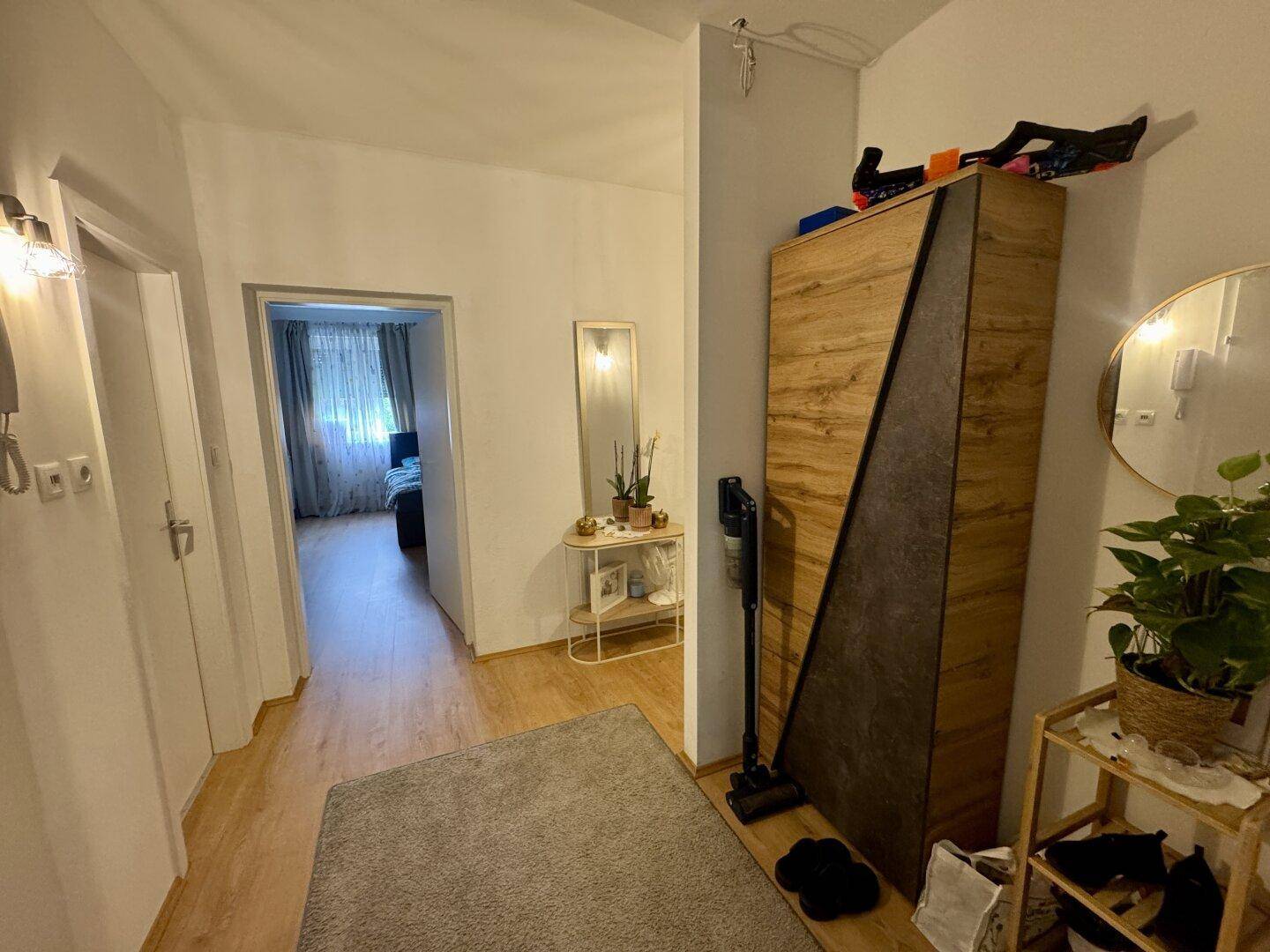 Geräumiger Flur mit Laminatboden, Spiegel und einem modernen Holzschrank.