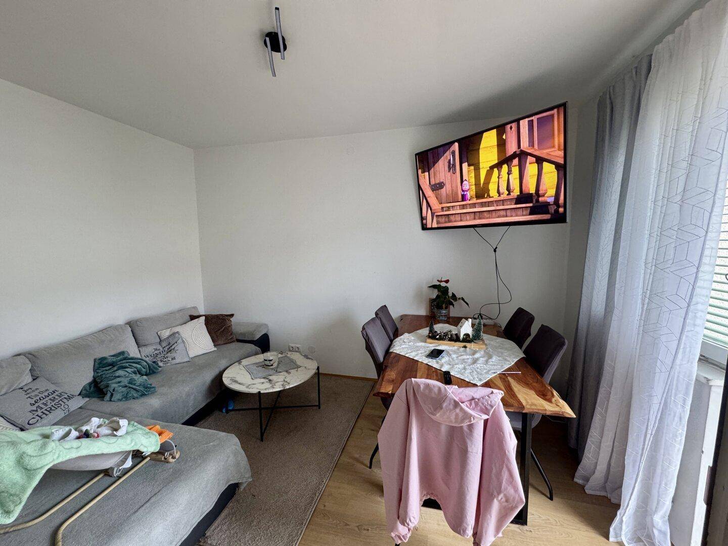 Gemütlicher Wohn-Essbereich mit Sofa, Esstisch und Fernseher, ausgestattet mit Laminatboden.