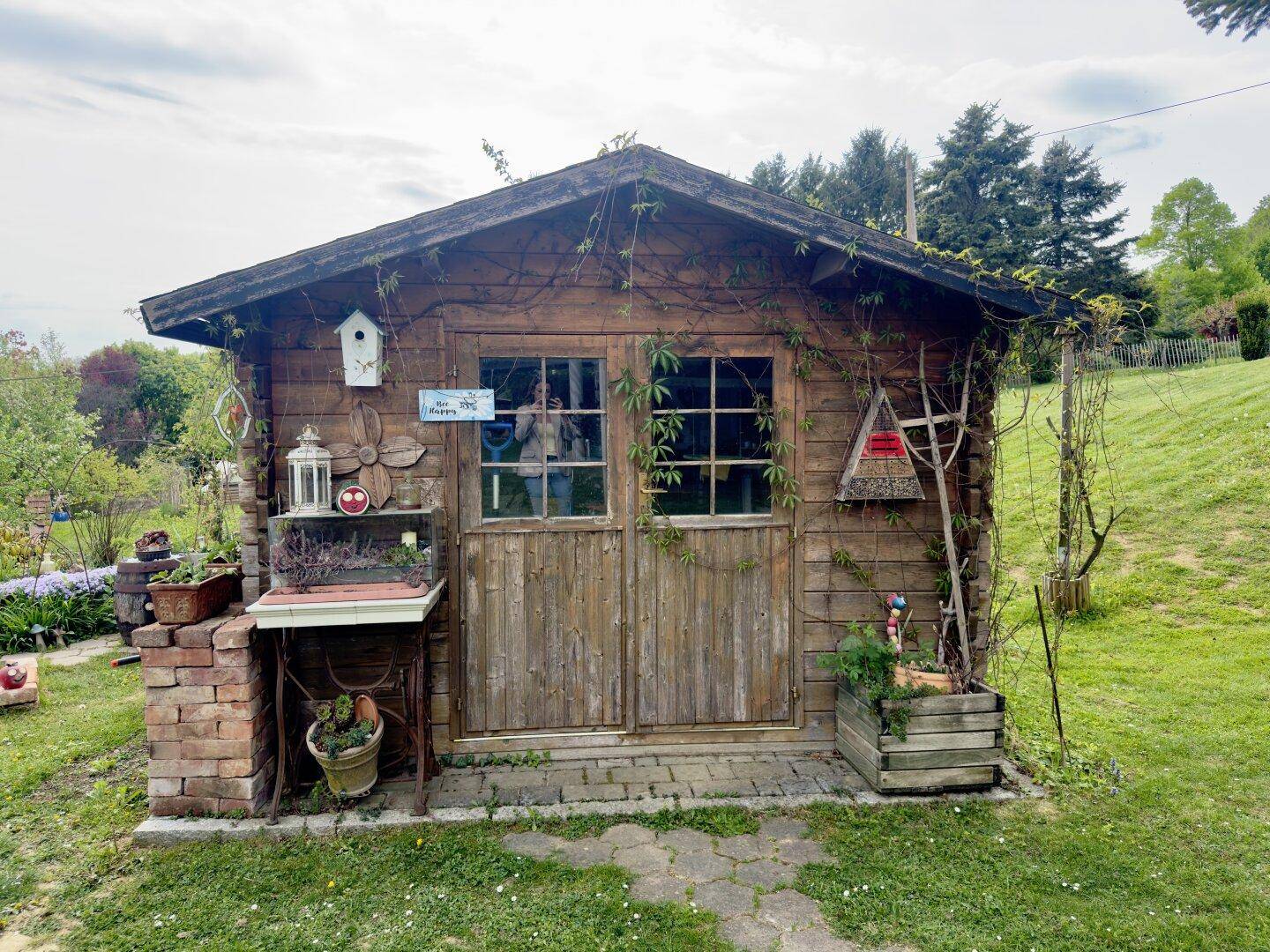 Charmantes Gartenhaus aus Holz mit rustikalen Türen und Fensterläden.