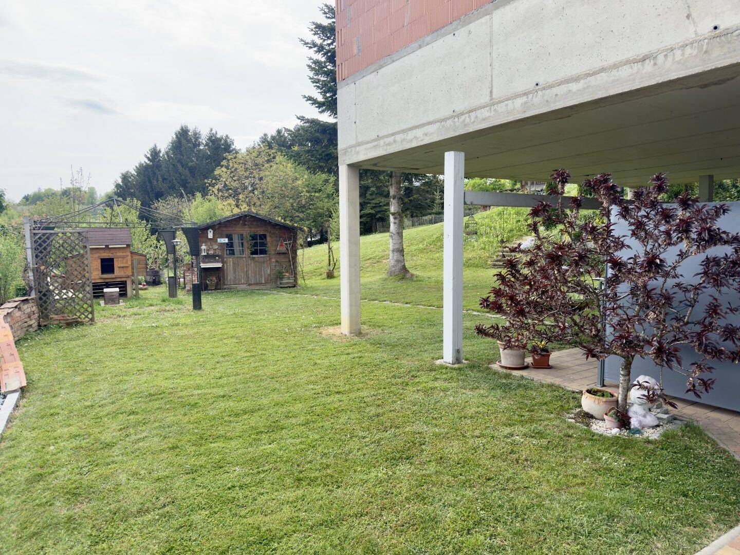 Gepflegte Rasenfläche mit Blick auf das Haupthaus und das Gartenhaus im Hintergrund.