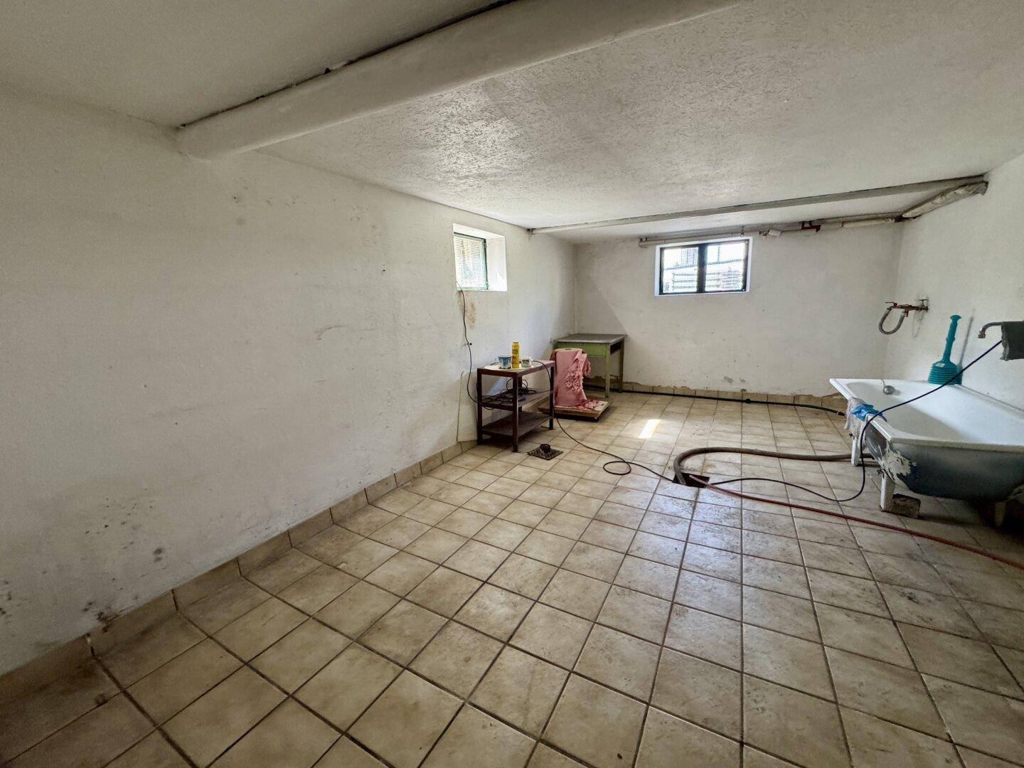 Geräumiger Hauswirtschaftsraum im Keller mit Fliesenboden und Waschbecken.